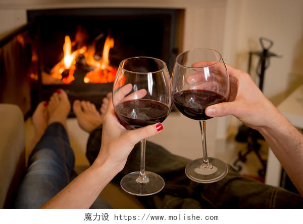 在开放的木火前喝酒对年轻的夫妇的特写.